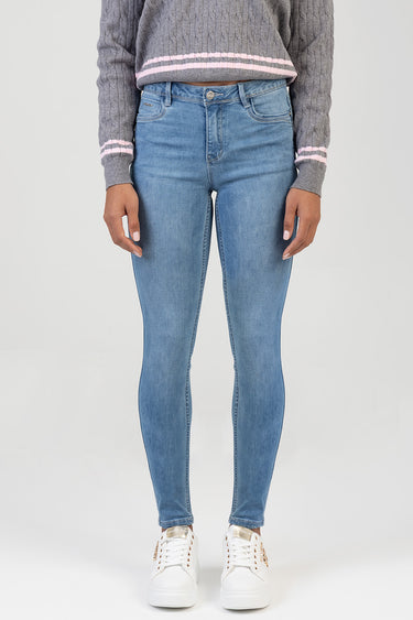 front view of light blue skinny jeans on a model, paired with a grey knit sweater with pink stripes and white sneakers