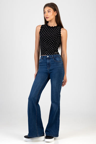 woman wearing a black sleeveless polka dot top and blue flare leg jeans