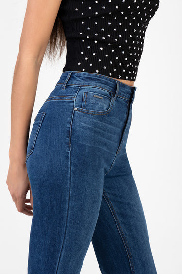 model wearing blue flare leg jeans with a back pocket and small brand tag, paired with a black embellished top