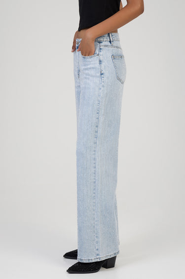 side view of a woman wearing light blue wide leg jeans with rhinestone stripes and black glittery heeled boots