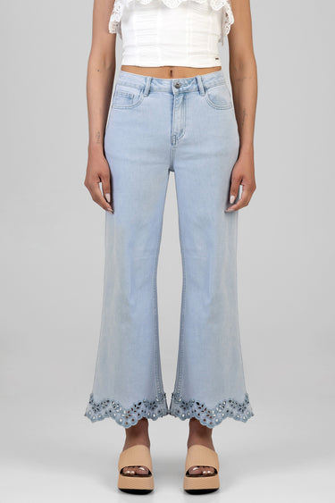 woman in a white cropped top wearing light blue cropped wide leg jeans with a scalloped lace hem and beige sandals