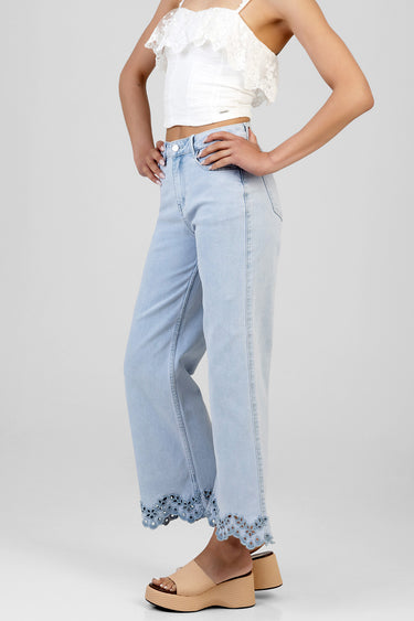 model wearing a white lace cropped top with ruffles and light blue wide leg jeans with scalloped lace hem