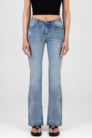 woman wearing light wash bootcut jeans with distressing and contrast stitching, paired with a black cropped top and black