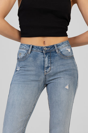 woman in a black cropped top and light wash distressed jeans by blue jean traders with patches on the knees