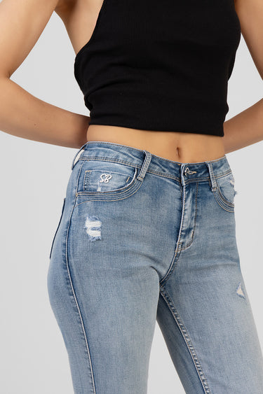 woman wearing blue jean traders bootcut jeans with distressed patches and contrast stitching, black crop top