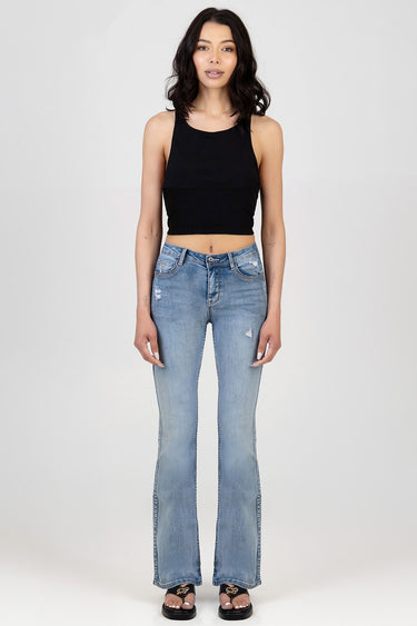 woman in black sleeveless crop top and light blue bootleg jeans with distressed details and black sandals