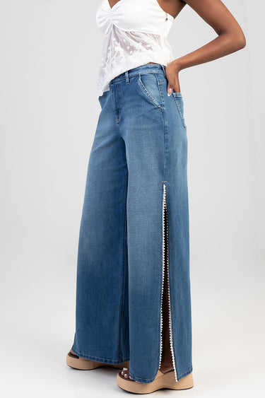 blue wide leg jeans with a beaded side slit, paired with a white lace top and tan sandals
