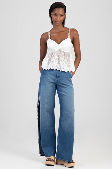 woman wearing light wash wide leg jeans with side slit and contrast panel, paired with a white lace top