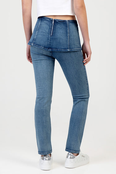 woman wearing light blue high waist jeans with back zipper, white cropped top, and white sneakers with silver accents on a