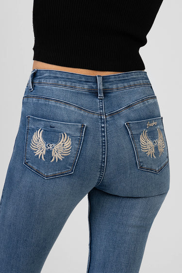blue skinny jeans viewed from the back with silver wing embroidery on the back pockets and a black knit top
