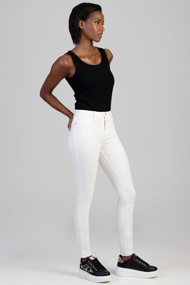 model wearing white skinny jeans with a black sleeveless top and black sneakers with white soles