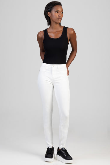 woman wearing a black sleeveless top and white skinny jeans with black sneakers by Blue Jean Traders