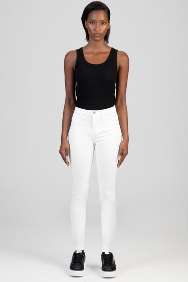 model wearing black sleeveless top with white skinny jeans and black sneakers