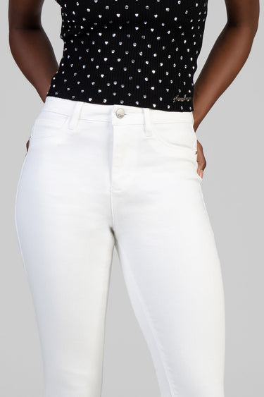 person wearing white skinny jeans and a black knit top with silver studs
