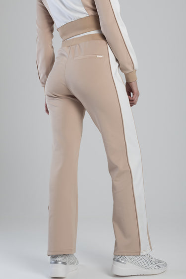 back view of beige track pants with white side stripe and rear welt pocket, worn with silver trainers.