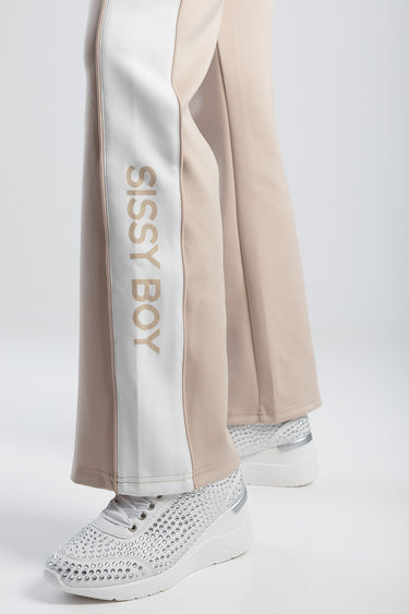 beige track pants with a white side stripe displaying bossy boy, paired with white rhinestone sneakers