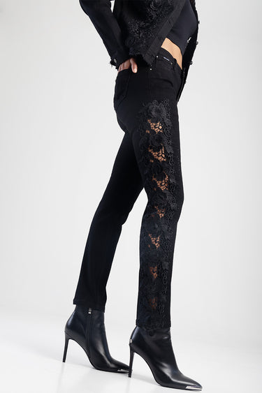 woman in black straight jeans with floral lace panels along the outer legs, paired with black heeled ankle boots