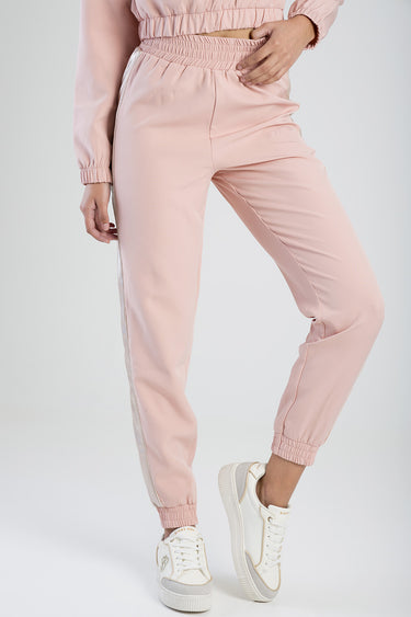 pink tracksuit pants with a white side stripe, elastic waistband and cuffs, paired with white sneakers