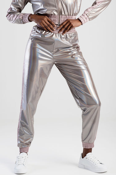 woman wearing metallic silver track pants with pink elastic waist and cuffs, white sneakers