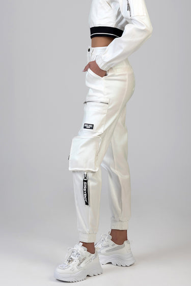 side view of white cargo pants with multiple pockets and zippers, paired with a cropped white jacket and chunky sneakers