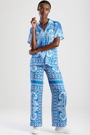 woman wearing blue and white printed pajama set with short sleeve top and wide leg pants, white sneakers