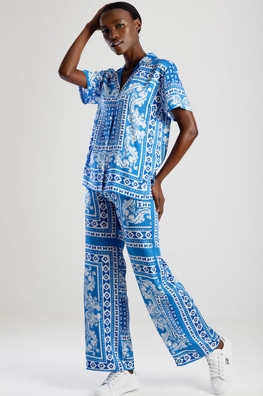 woman wearing a blue and white patterned shirt and matching wide leg pants with white sneakers