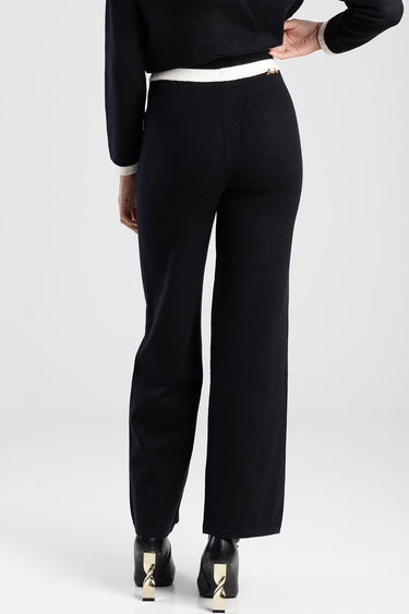 Blue Jean Traders knit pants, back view showing navy fabric, white waistband trim, and wide legs with black heeled shoes