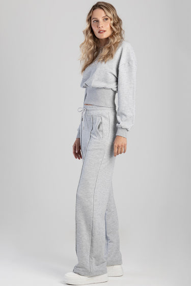 woman in light gray fleece sweatpants with a drawstring and pockets, paired with a matching cropped sweatshirt