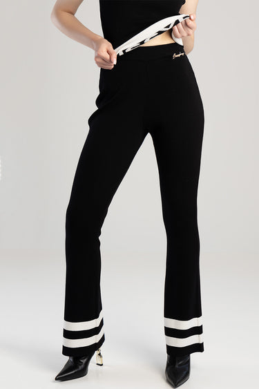 black knit pants with a slim waist and wide legs, white striped cuffs at the hem, small gold logo at the hip
