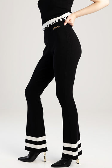 blue jean traders black knit pants with a white elastic waistband and gold logo, white stripe cuffs, black heeled boots