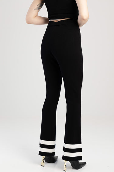 back view of black knit pants with white stripes at the cuffs and a flared hem worn by a model