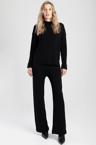 woman wearing black knit pants and matching black sweater, full body pose
