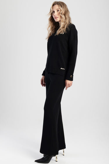full length side profile of a woman wearing a black knit sweater and matching wide leg pants with heeled boots by Blue Jean