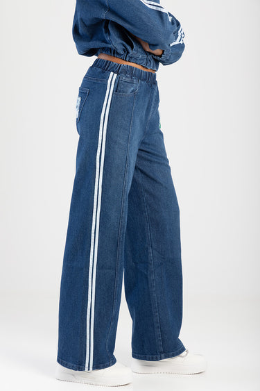 person wearing blue denim track jeans with two white side stripes, wide leg, and white sneakers