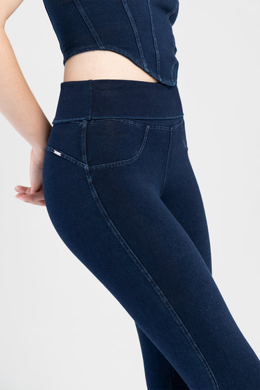 side view of a person wearing dark indigo audrey flare jeans with a high waistband; back pocket shows a small brand tag