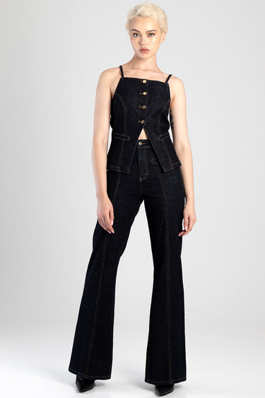 woman wearing dark indigo flare jeans with a matching sleeveless denim vest and gold buttons