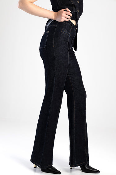 side view of a person wearing dark wash flare jeans with high waist and orange stitching, black heeled boots