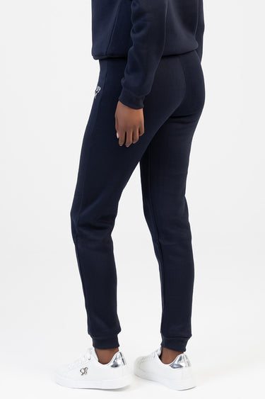 woman wearing navy blue jogger pants with rib cuffs and a small white logo at the hip, paired with white sneakers