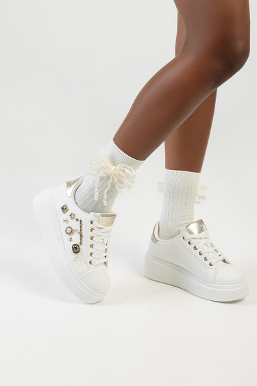 legs wearing ivory socks with a pearl bow at the ankles paired with white platform sneakers with metallic accents
