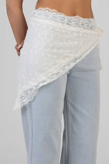 white floral lace wrap draped around the hips over light blue jeans