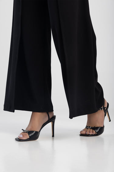 woman wearing black wide leg trousers and black open toe heeled sandals with ankle straps