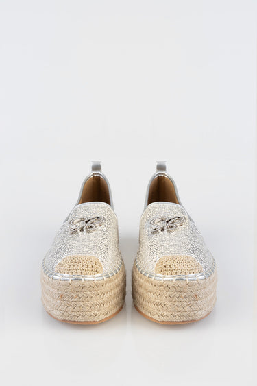 pair of silver espadrille flats with woven jute platform and metallic upper, braided trim and decorative emblem.