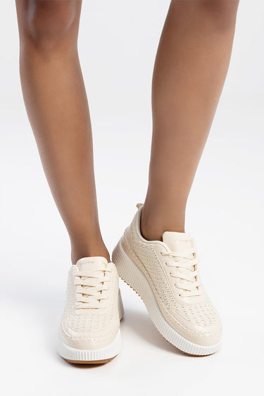 creamy beige sneakers with a knitted upper and chunky white sole worn by a person