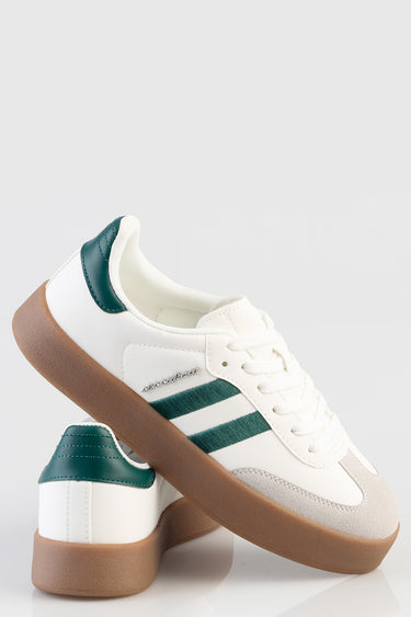 white sneakers by blue jean traders with green stripes teal heel panel and gum sole