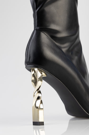 black leather boot with a twisted gold metal heel, close view of back seam and sole rounding