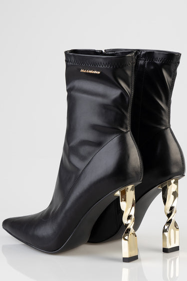 black ankle boots with pointed toes and sculptural gold heel accents