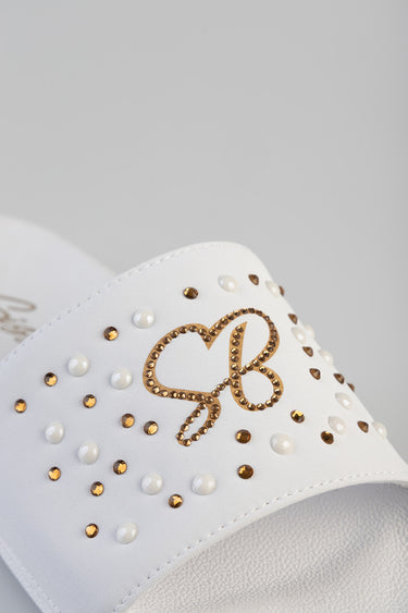 white leather slide sandal with gold and white stud embellishments and a decorative gold logo on the strap