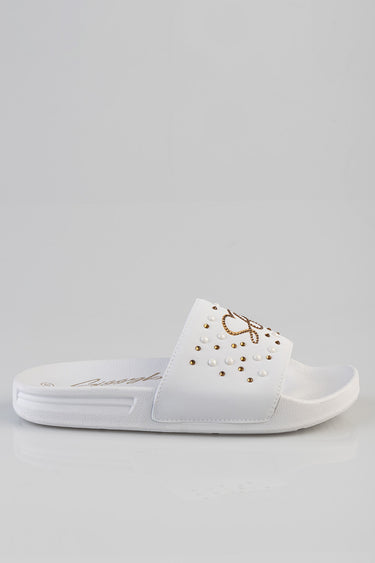 white slide sandal with a studded and pearl-embellished strap on a white sole