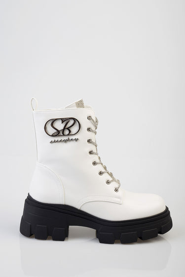 white ankle boot with a thick black lug sole, lace-up front and metallic logo patch on the side