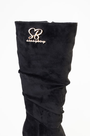 black suede knee high boot with a slouched shaft and a gold initials emblem on the upper front